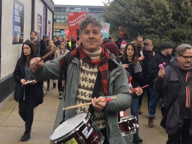 David Harvie drumming ahead of a march of protestors