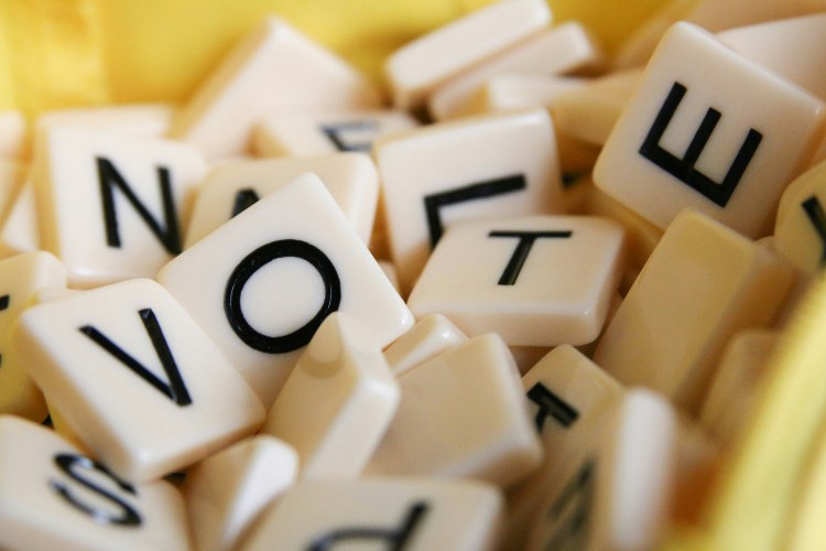 Scrabble tiles spell out the word 'vote'.
